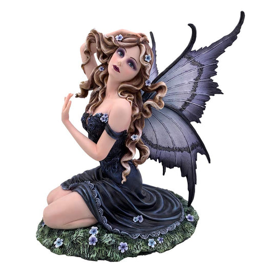 Fairy figurine kneels on a grassy base, tilting her head upward with hands near her hair, wearing a dark flowing dress and large purple wings, surrounded by small pale flowers.