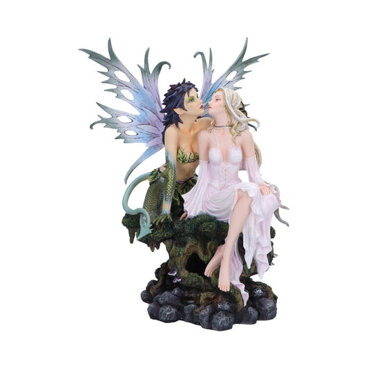 Two fairy figurines: a green-scaled, winged fairy leans forward to kiss or whisper a seated blonde in flowing pink dress, both perched on a mossy rocky base against white.