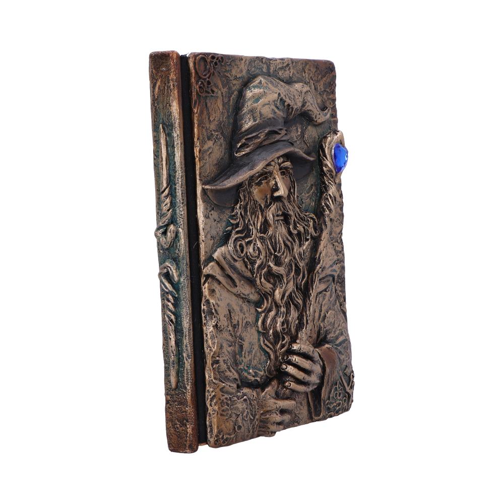 Ornate bronze book-shaped box embossed with a robed wizard who holds a staff topped by a blue gem, the detailed cover angled against a plain white background.