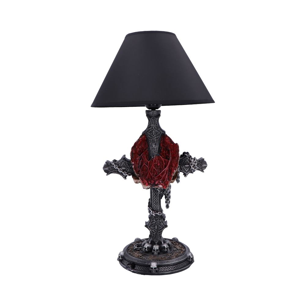 Gothic table lamp stands with black conical shade, ornate metallic cross-shaped base wrapped in a sculpted red heart and chains, skull-adorned round pedestal on white background.