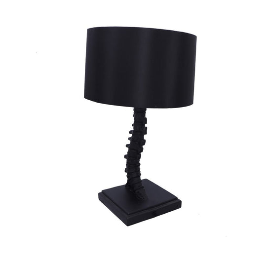 Black table lamp with spine-shaped stem supports a cylindrical black shade and stands on a square base against a white background.
