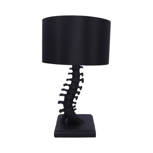 Black table lamp with a cylindrical shade stands on a square base, its stem shaped like a human spine and foot, isolated against a white background.