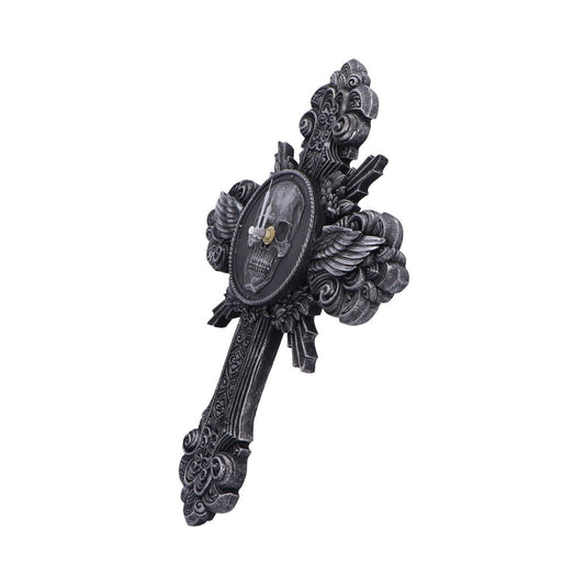 Ornate cross-shaped wall clock displays clock hands over a central skull medallion with winged and baroque flourishes against a plain white background.