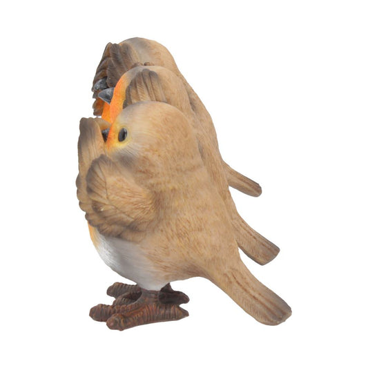 Three bird figurines stand together. They are pale brown with white underparts and have orange beaks. They are set against a white background.