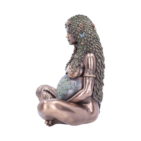 A bronze-colored statuette depicts a woman sitting cross-legged, covered in leafy adornments. She cradles a globe, symbolizing earth, with intricate designs in a minimal, white backdrop.