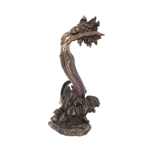 A bronze mermaid statue arches gracefully backward, hair flowing and tail shimmering, emerging from stylized ocean waves. The base is detailed with aquatic elements.