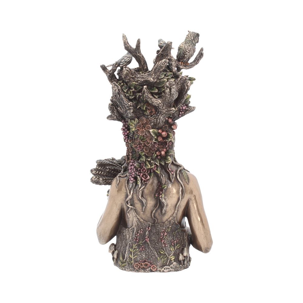 A detailed sculpture resembles a human torso blending into a tree trunk, adorned with carved branches, leaves, and animals. The setting is plain, drawing focus to the intricate design.