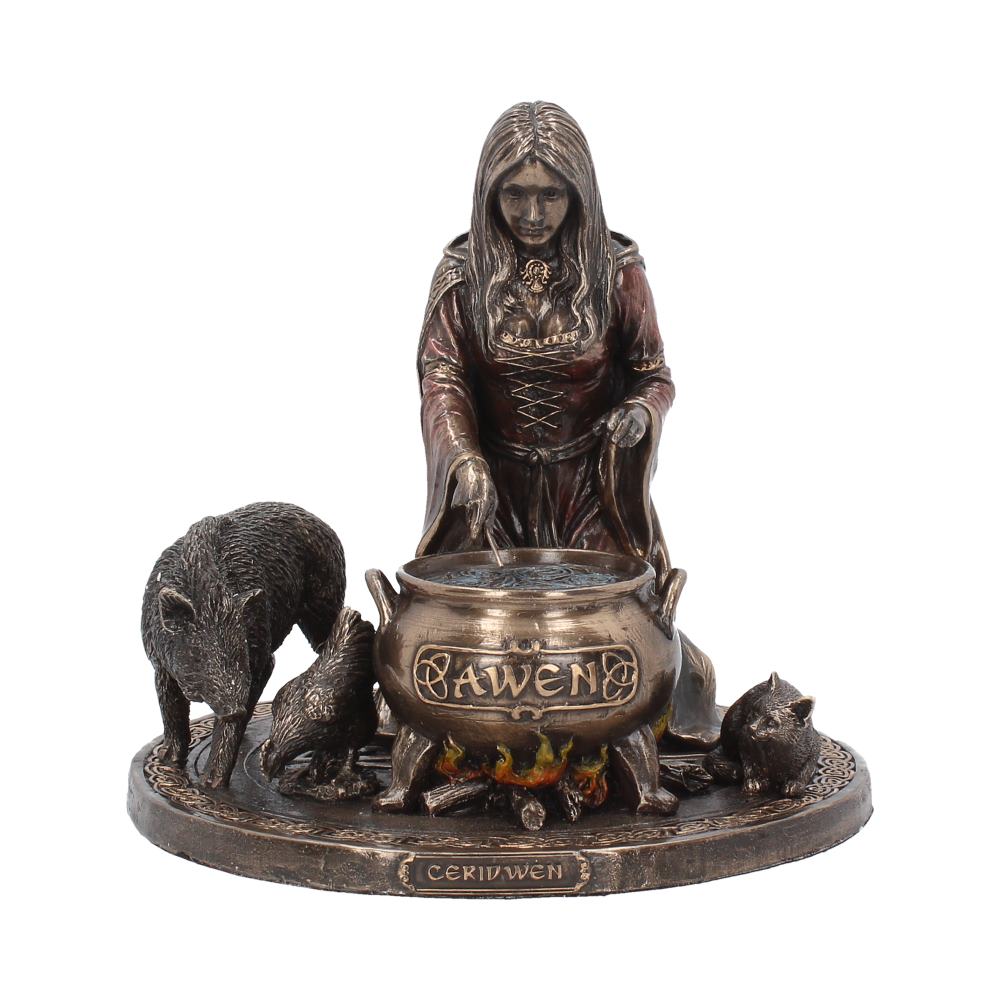 A bronze-colored statue depicts a robed woman stirring a cauldron inscribed with "AWEN" over a fire, surrounded by a pig, a rooster, and a cat. The base reads "CERIDWEN."