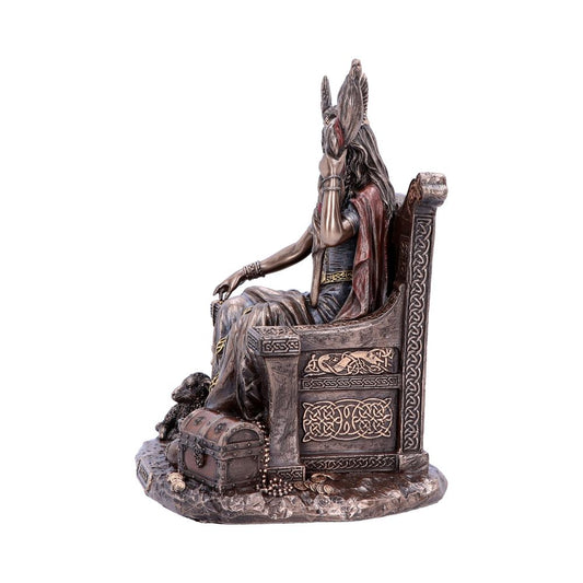 A detailed statue depicts a seated figure wearing a horned headdress on an intricately carved throne, accompanied by a chest and animal at the base, set against a plain background.