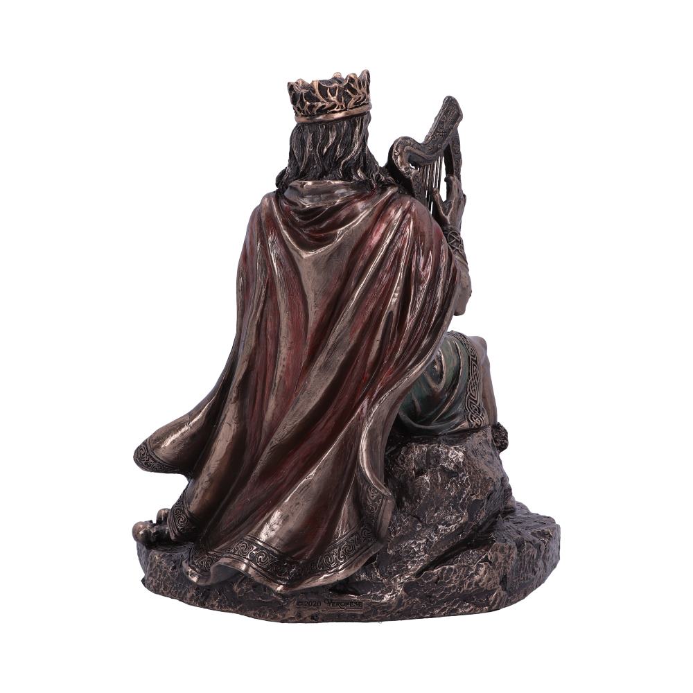 A bronze-colored sculpture depicts a king wearing a crown and cloak, seated on rocks while playing a harp. The figure faces away, suggesting a contemplative, solitary scene.
