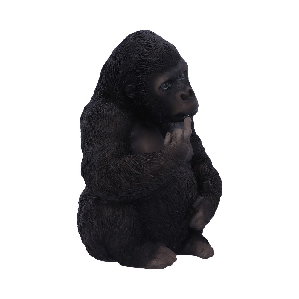 A dark-furred gorilla sits against a plain white backdrop with a pensive expression, holding its finger to its chin in a thoughtful pose.