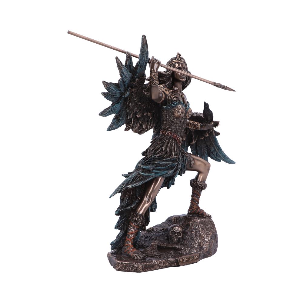 A warrior statue with wings holds a spear and raven, standing on a rocky base adorned with a skull. The base has the inscription “Morrigan.”