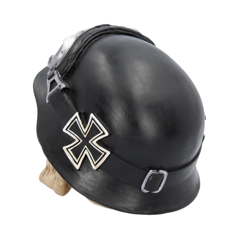 Black helmet with cross emblem, worn by a skull, resting on a flat surface. The helmet features a strap with metal accents, creating a vintage military appearance.