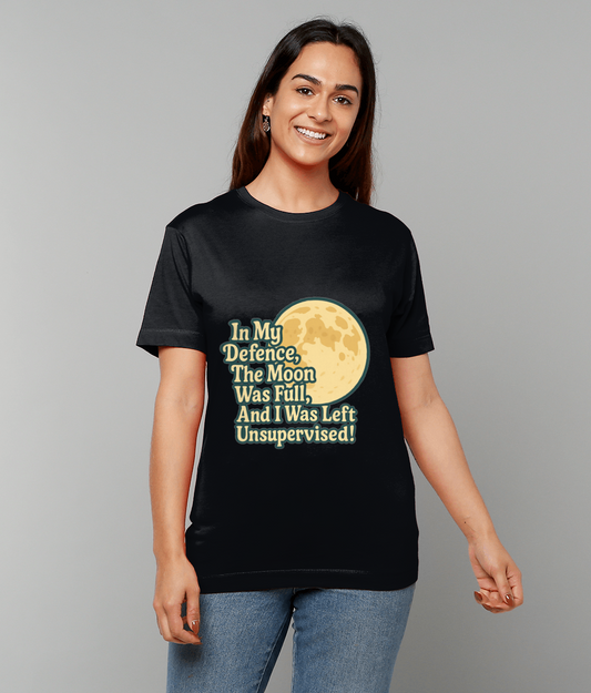 Black T-shirt displays a large moon graphic and the text "In My Defence, The Moon Was Full, And I Was Left Unsupervised!" while a smiling person stands against a plain gray background.