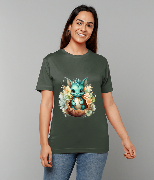 Teal baby dragon sits in a cracked eggshell surrounded by pastel flowers printed on the center of a dark green t-shirt worn by a smiling woman against a gray background.