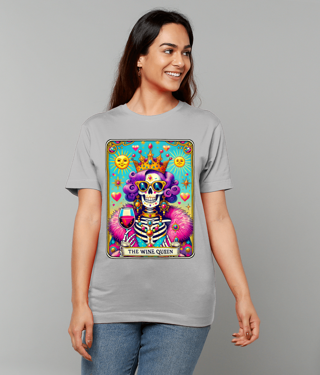 T-shirt graphic shows a crowned skeleton queen holding a glass of red wine on a colorful tarot-style card printed on a gray shirt worn by a smiling woman against a plain gray background. Text: "THE WINE QUEEN"