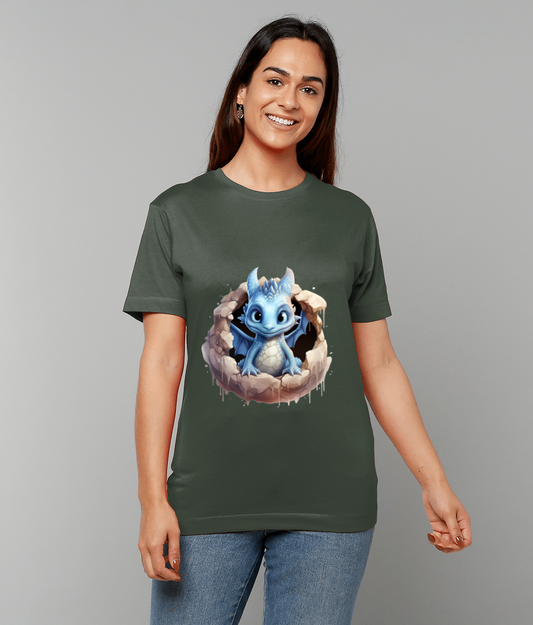 Blue baby dragon emerges from a cracked eggshell as a printed design on an olive green T-shirt worn by a smiling woman standing against a plain gray background.