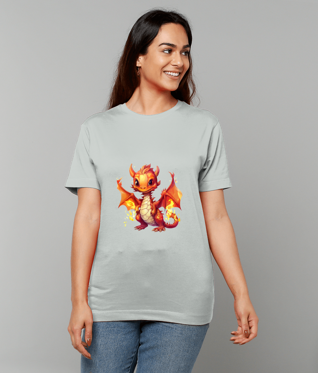 A pale gray T-shirt displays a smiling orange baby dragon standing with wings raised and small flames, worn by a smiling woman against a plain light gray studio background.