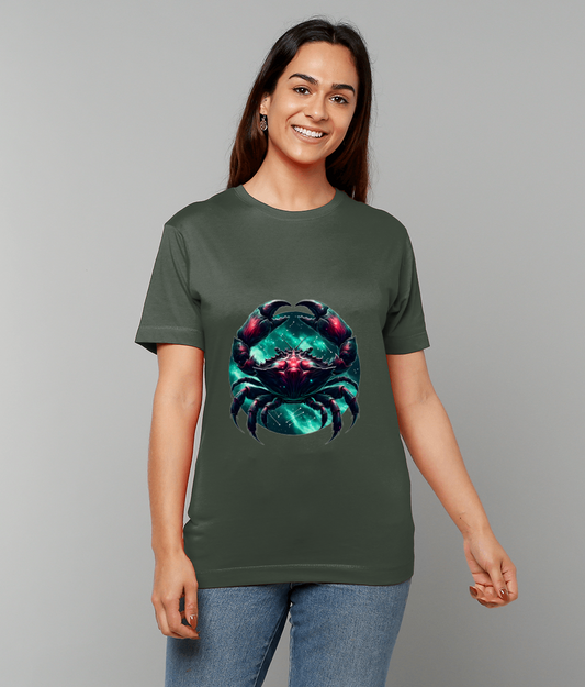 Neon teal and magenta crab graphic centered on an olive-green T-shirt, displayed on a smiling woman standing against a gray studio backdrop wearing blue jeans.