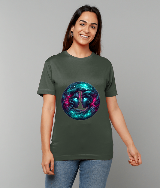 T-shirt graphic shows two luminous mirrored faces in a swirling cosmic orb while a person smiles and stands against a plain light gray backdrop wearing a green shirt and jeans.