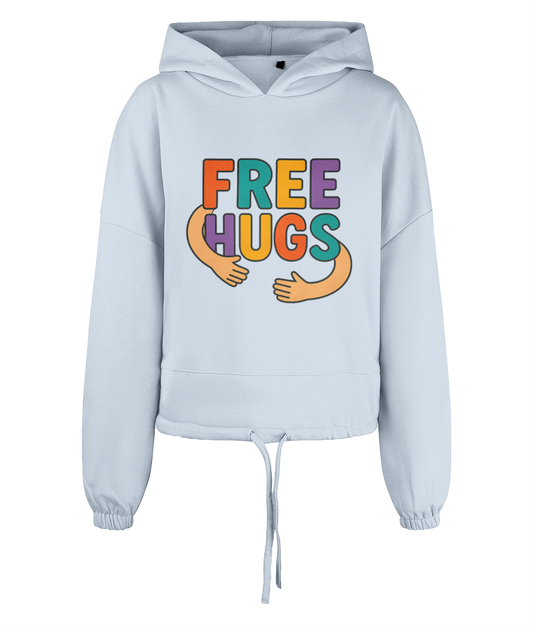 Light blue cropped hoodie displays colorful text "FREE HUGS" with two cartoon arms forming a hug on its chest, front-facing against a plain black background.