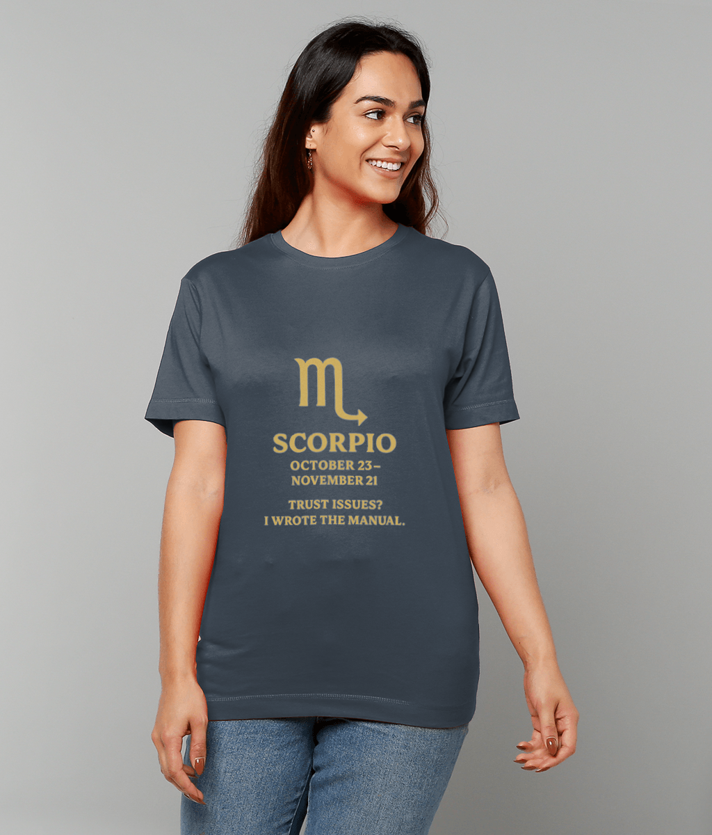 Woman wearing a dark gray T-shirt with a gold Scorpio glyph and text, smiling and standing against a plain light-gray background: ♏ SCORPIO OCTOBER 23 - NOVEMBER 21 TRUST ISSUES? I WROTE THE MANUAL.