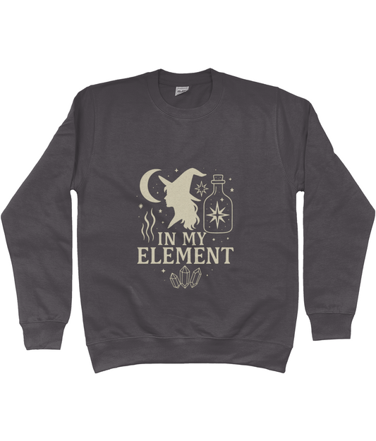 Dark gray sweatshirt displaying a witch silhouette, crescent moon, potion bottle, stars and crystals with the text IN MY ELEMENT centered on the front in light print.