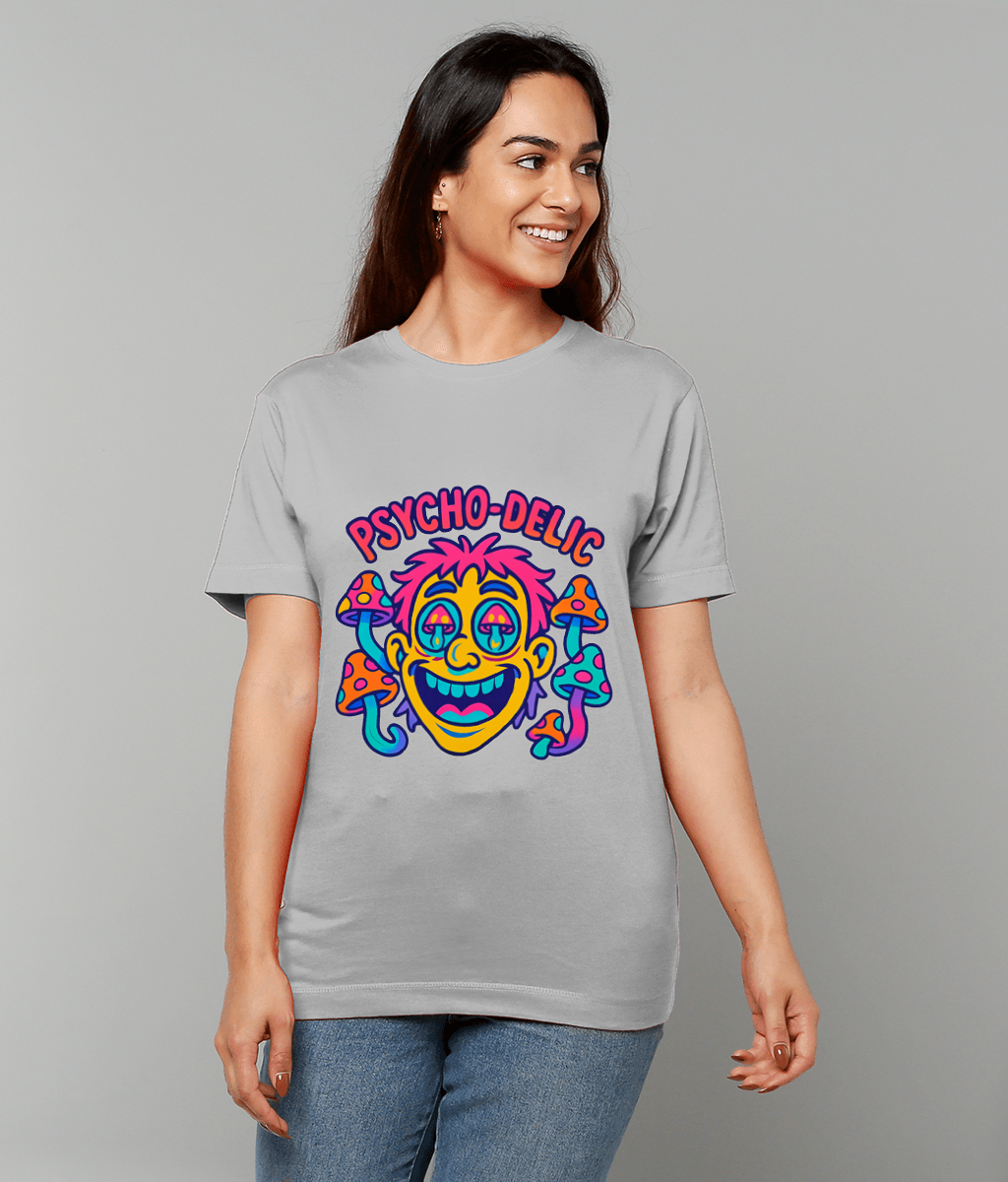 Gray t-shirt graphic shows a neon cartoon face surrounded by colorful mushrooms labeled "PSYCHO-DELIC", worn by a smiling woman looking to the side against a plain light gray studio background.