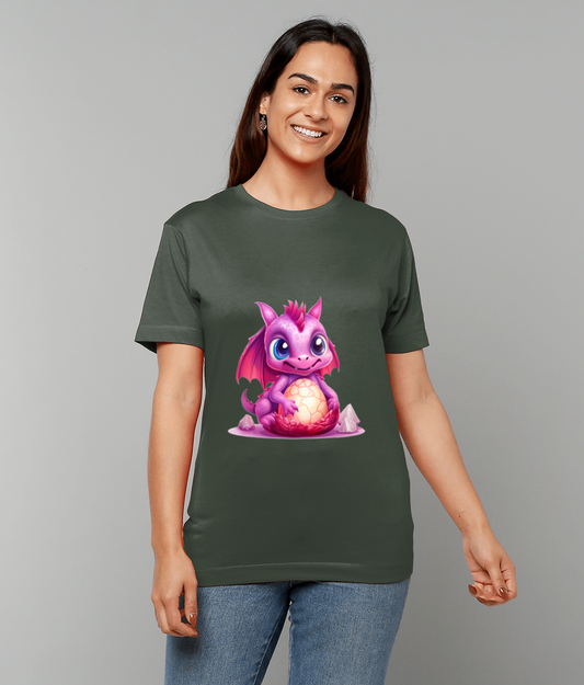 Purple baby dragon sits clutching a glowing cracked egg on a dark green T-shirt worn by a smiling woman standing against a plain gray background.