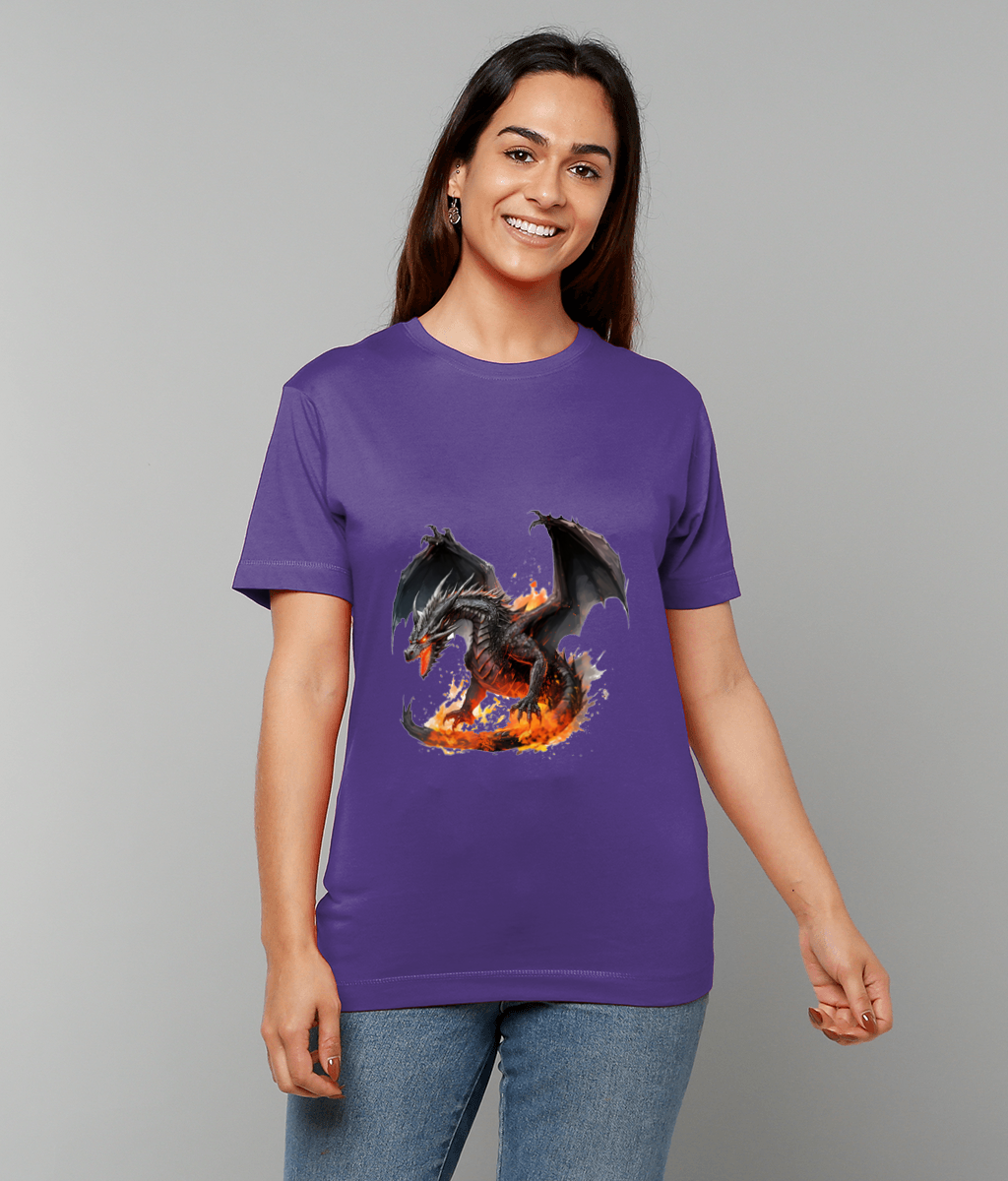 Smiling woman wearing a purple T-shirt that displays a black dragon breathing fire and rising from flames, standing against a plain gray studio backdrop while she wears blue jeans.