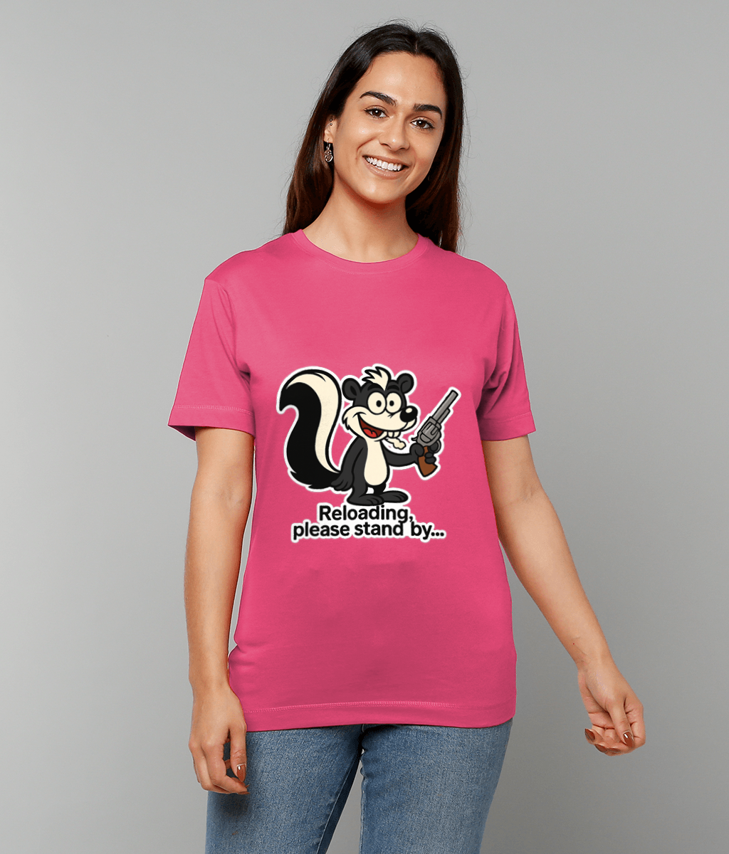 Skunk graphic holding a revolver on a pink T-shirt worn by a smiling woman against a plain gray background; text: "Reloading, please stand by..."