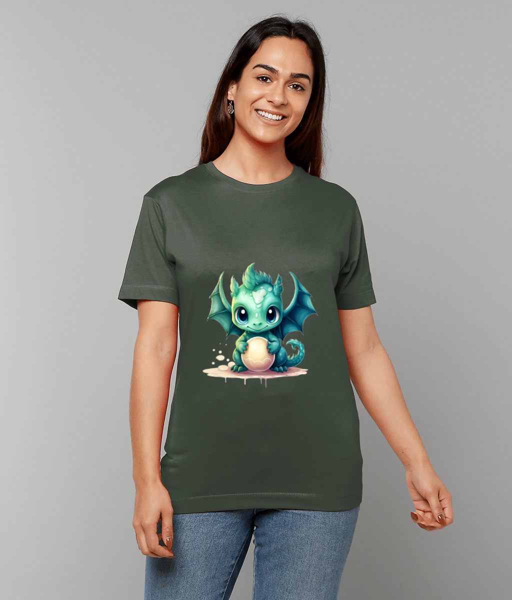 Small turquoise baby dragon sits clutching a pale egg on a t-shirt worn by a smiling person against a plain gray background.