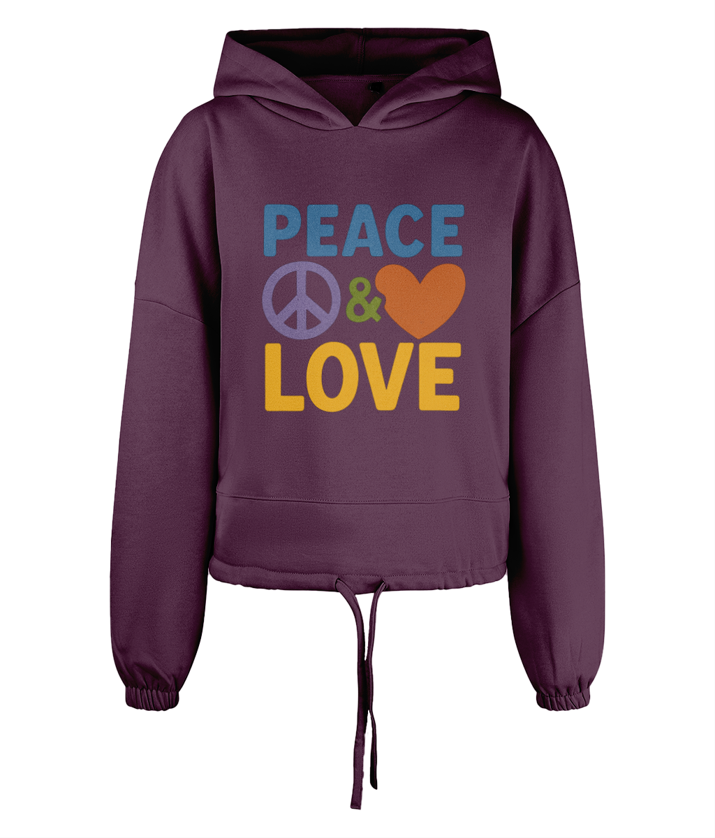 Purple cropped hoodie displays PEACE & LOVE with a peace symbol before the ampersand and a heart after it centered on its chest against a plain black background.