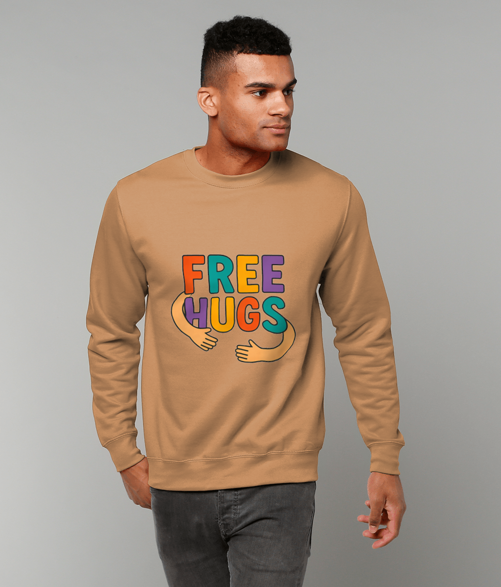 Beige sweatshirt displaying "FREE HUGS" in colorful letters with cartoon arms hugging, worn by a young man standing against a plain gray background.