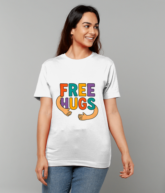 White T-shirt reading "FREE HUGS" worn by a smiling woman looking right; colorful letters include cartoon hugging arms, she stands in jeans against a plain gray background.