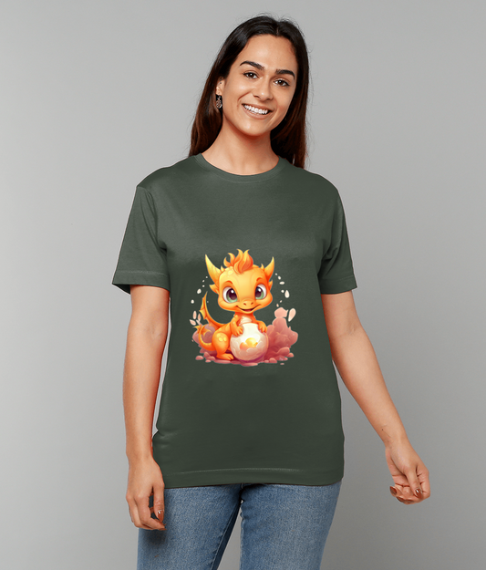 A smiling woman wears an olive-green T-shirt displaying a bright orange baby dragon cradling a glowing egg against a neutral gray studio background.