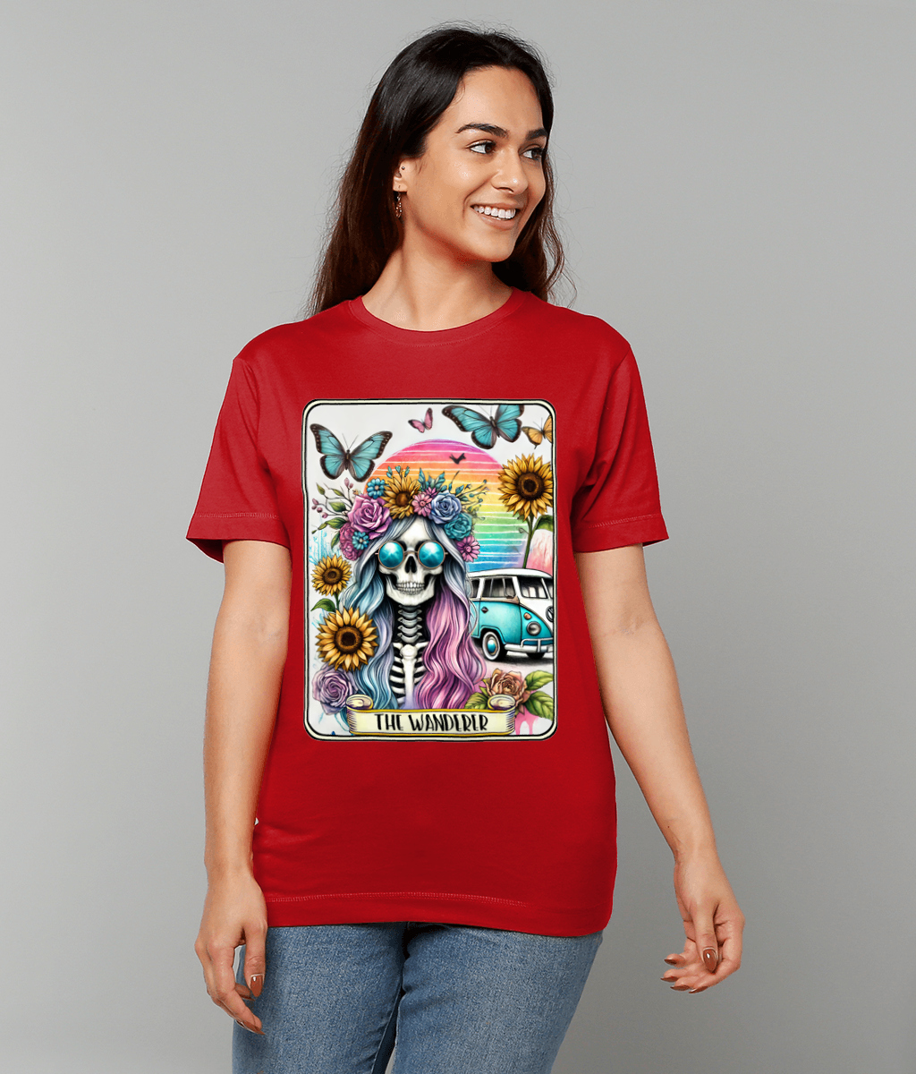 T-shirt graphic shows skull with pastel hair, flower crown, sunglasses, surrounded by sunflowers, butterflies and teal van; worn by smiling woman on gray background; text: THE WANDERER