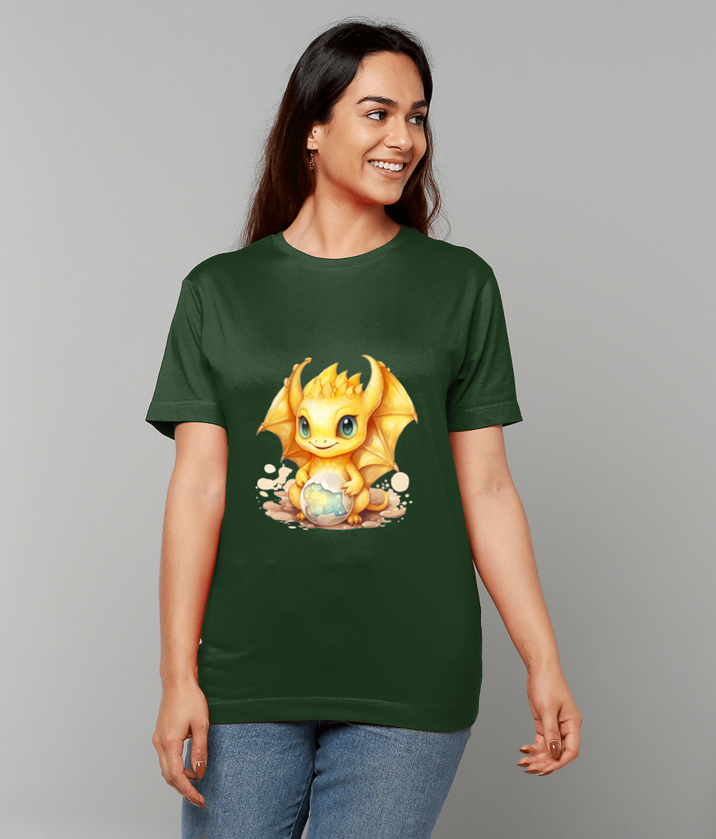 Yellow cartoon baby dragon on a green T-shirt, sitting and clutching a glowing orb, worn by a smiling person standing against a plain light gray background.