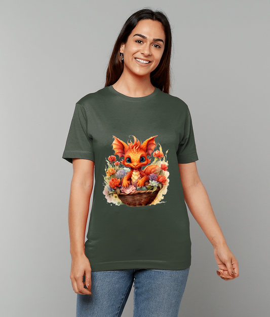 T-shirt displays a bright orange baby dragon sitting in a wicker basket amid colorful flowers, modeled on an olive-green tee worn by a smiling woman against a plain light-gray background.