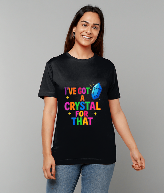 Person wearing a black T-shirt displays colorful text "I'VE GOT A CRYSTAL FOR THAT" alongside a blue crystal graphic while standing smiling against a plain light-gray studio background.