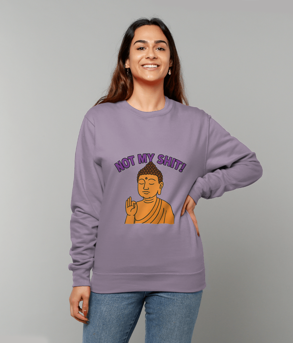 Lavender sweatshirt displays text "NOT MY SHIT!" above a cartoon Buddha making a hand gesture, worn by a smiling woman standing against a plain gray background.