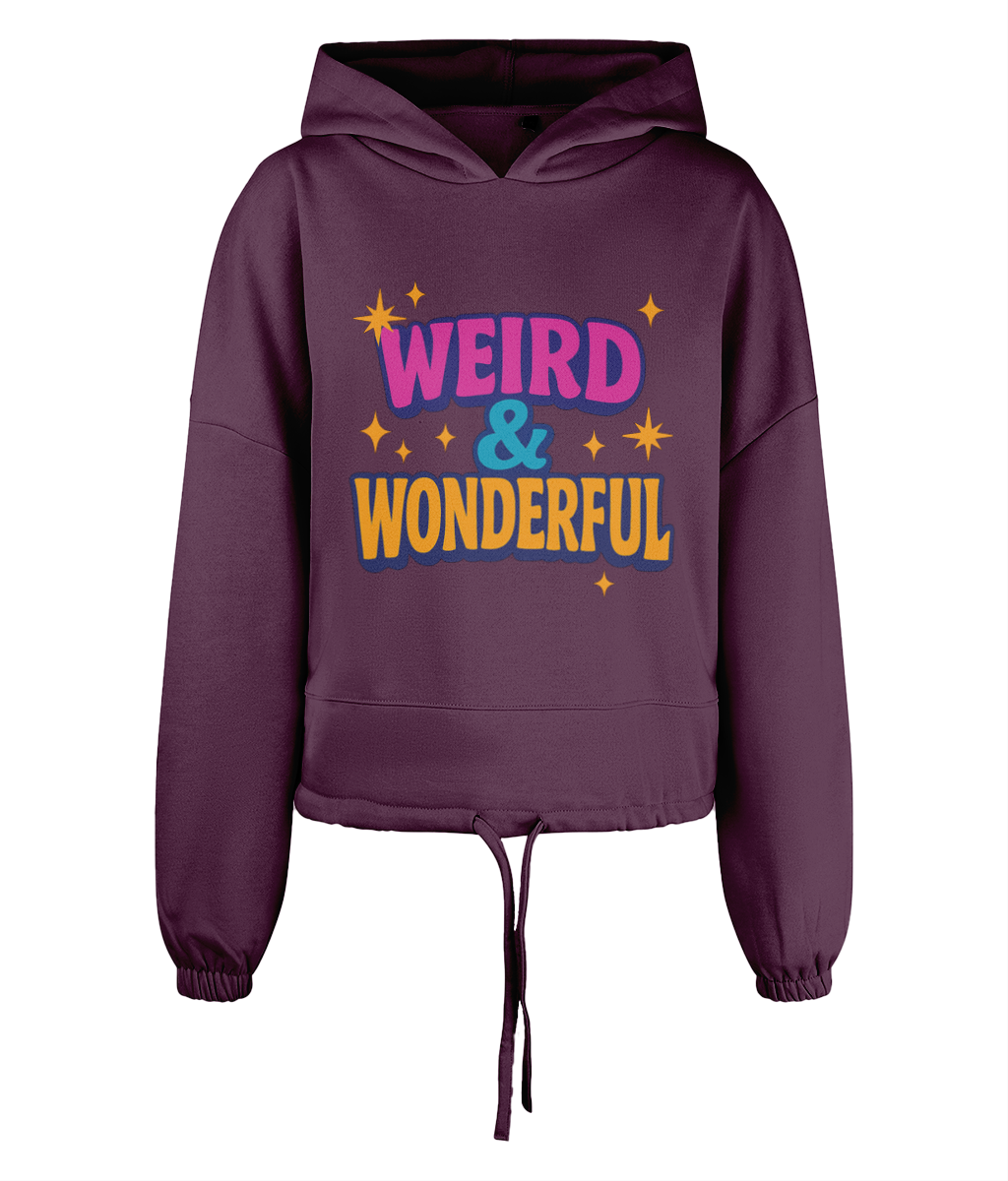 Hoodie shows printed slogan WEIRD & WONDERFUL in colorful bold letters with small yellow star motifs across the chest on a cropped plum hoodie against a black background.