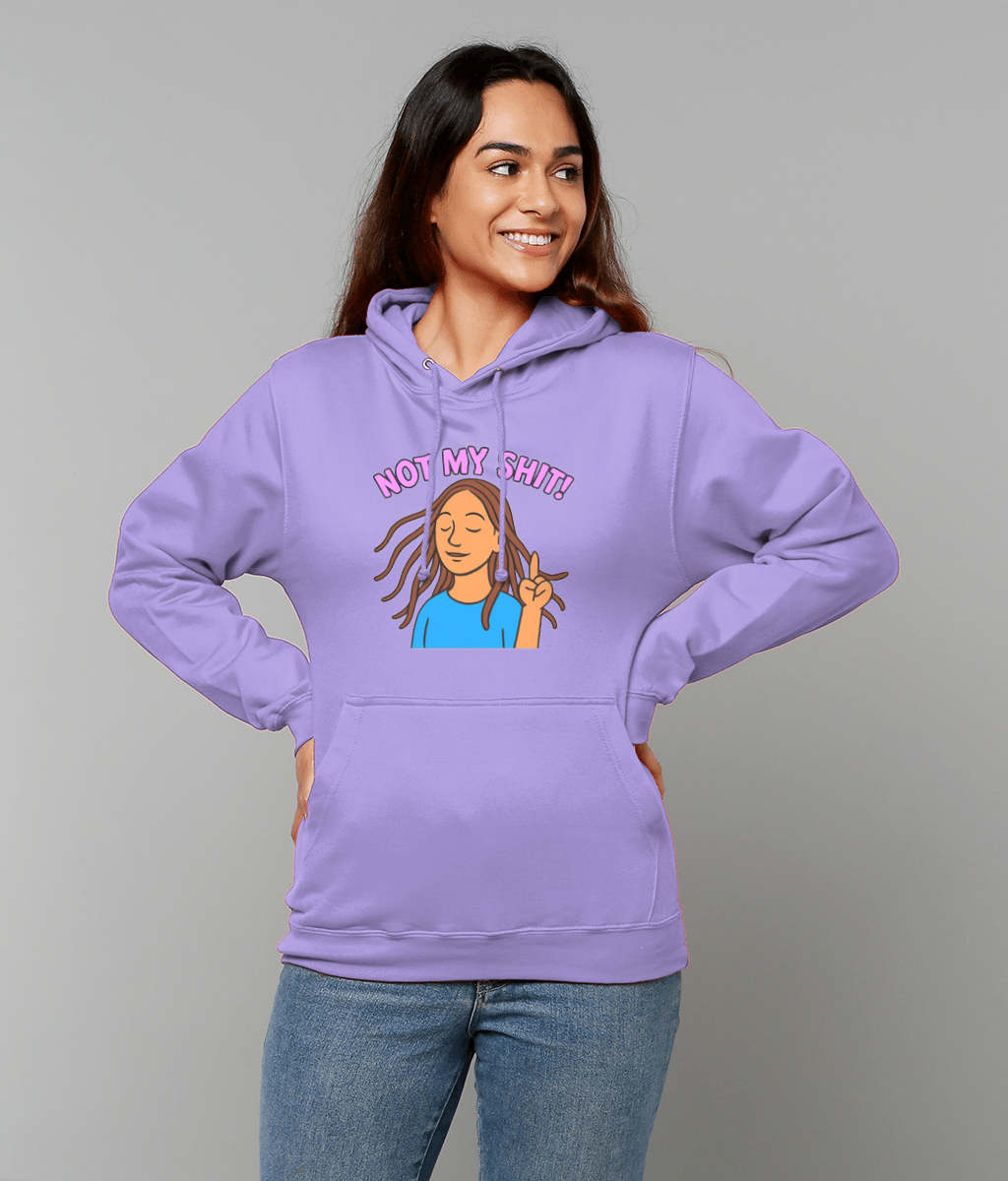 Woman wearing lilac hoodie printed "NOT MY SHIT!" stands with hands on hips smiling in blue jeans against a plain light gray background.