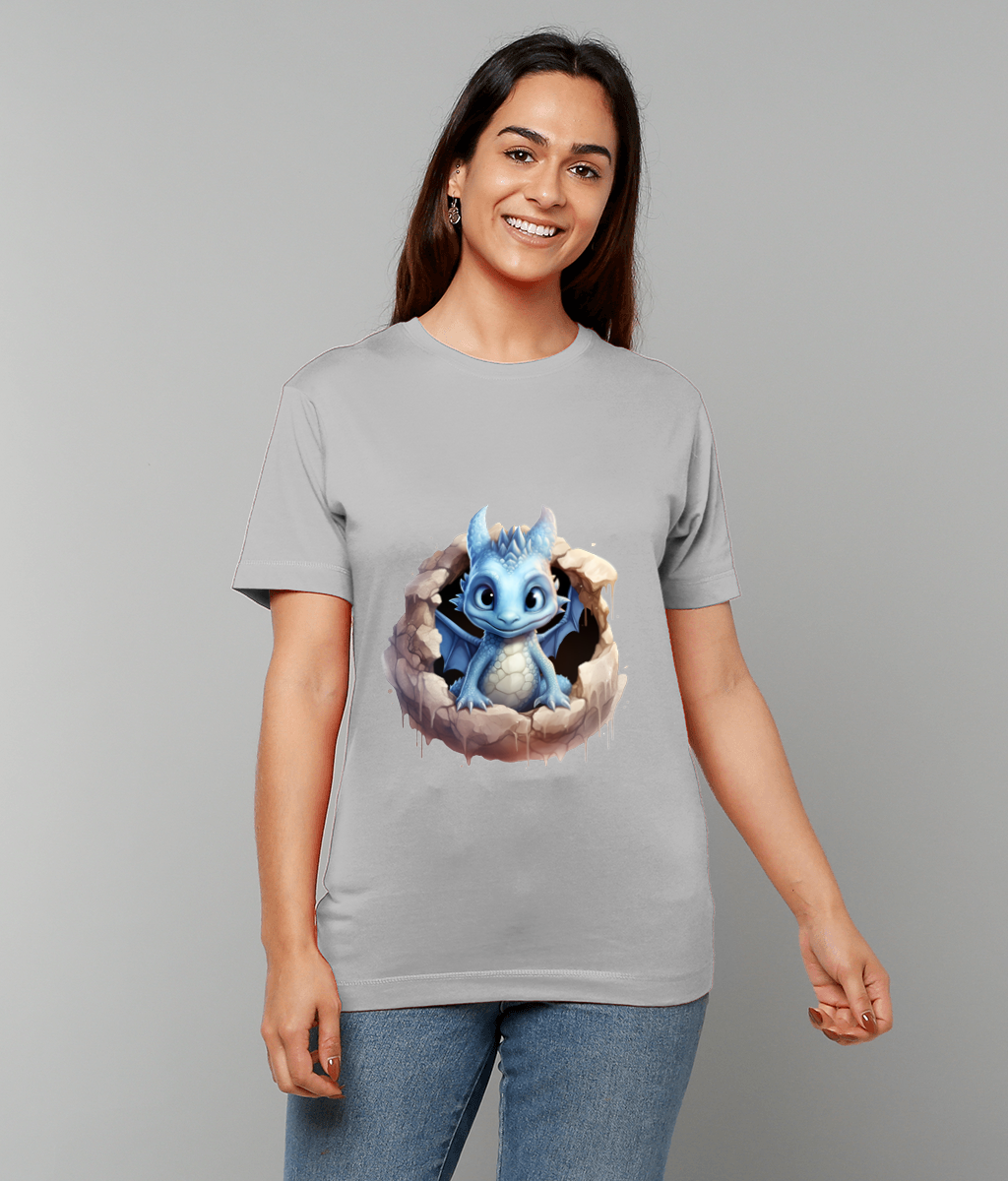 A blue baby dragon pokes out of a cracked eggshell printed on a light gray T-shirt worn by a smiling woman standing against a plain neutral background.