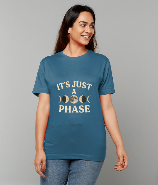 Blue T-shirt reading "IT'S JUST A PHASE" worn by a smiling woman looking right against a plain gray background.
