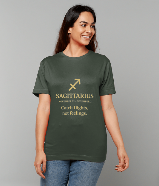 Dark green T-shirt bearing a gold Sagittarius arrow and text "SAGITTARIUS NOVEMBER 22 - DECEMBER 21 Catch flights, not feelings." worn by a smiling woman standing against a plain gray background.