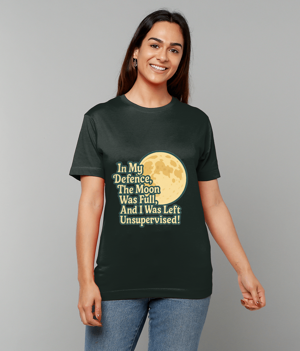 T-shirt displays the text "In My Defence, The Moon Was Full, And I Was Left Unsupervised!" worn by a smiling woman standing against a plain light gray background.