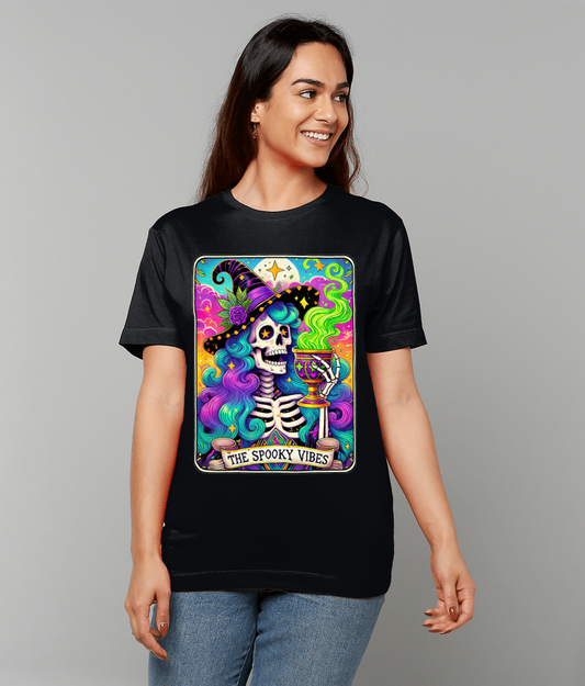 Woman wearing a black t-shirt displaying a colorful skeleton witch holding a smoking goblet against a vibrant cosmic background, text reads "THE SPOOKY VIBES".