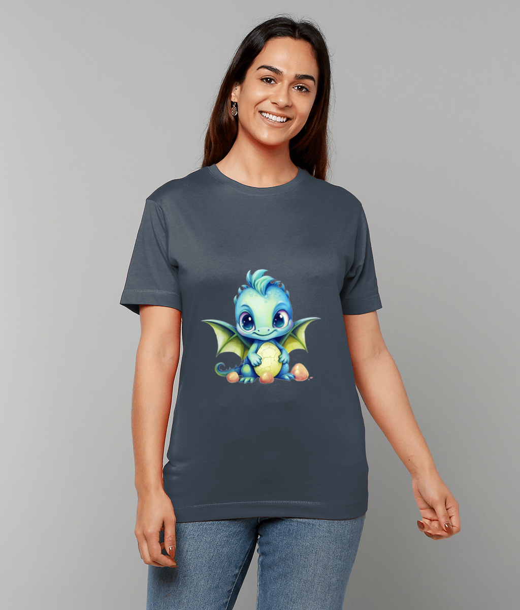 T-shirt features a chubby blue baby dragon cradling partially cracked egg while sitting among small eggs; smiling woman models dark gray tee and jeans against neutral gray background.