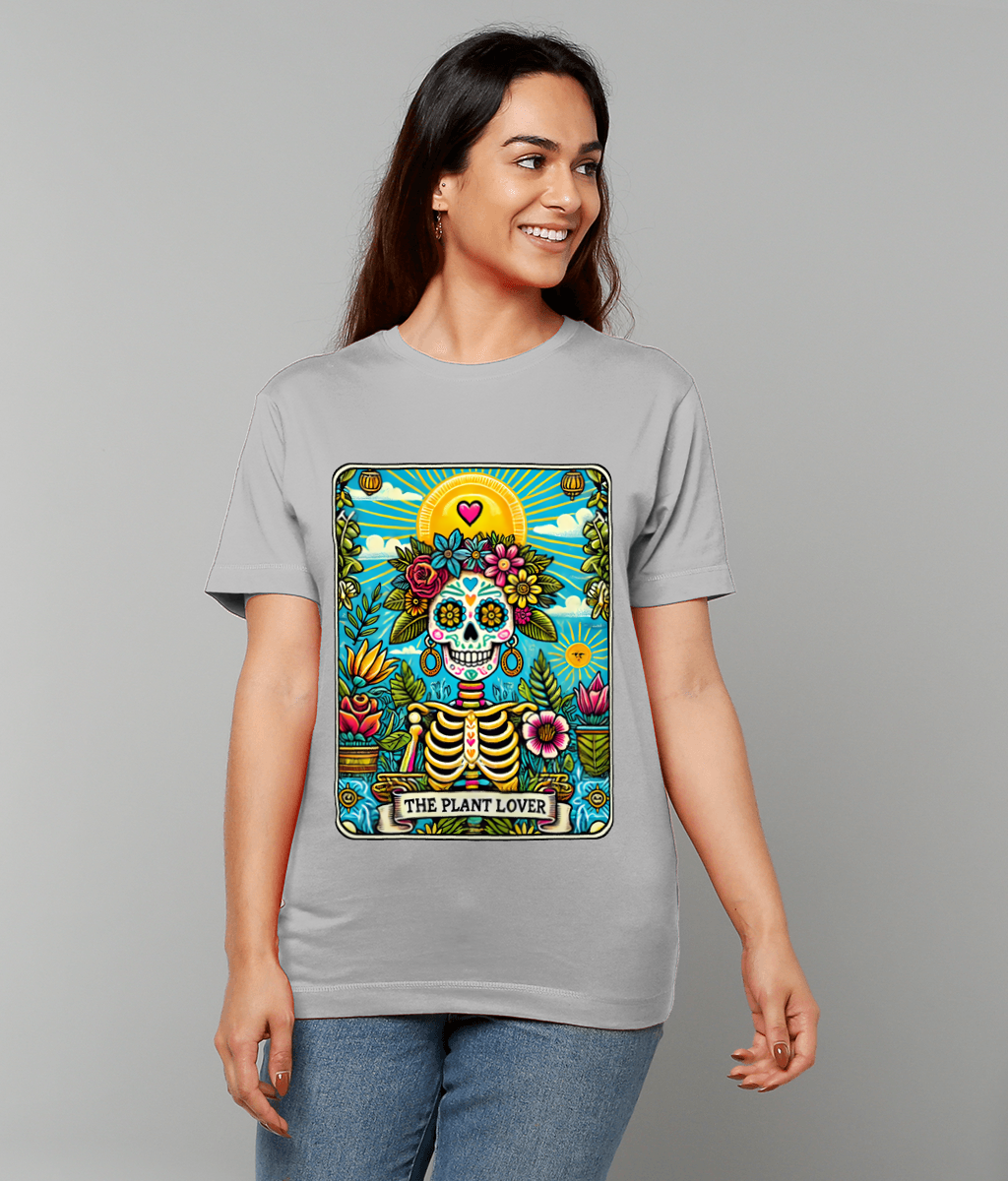 T-shirt displays a colorful Day of the Dead sugar skull with floral crown and plants, worn by a smiling woman against a plain gray background, banner reads THE PLANT LOVER